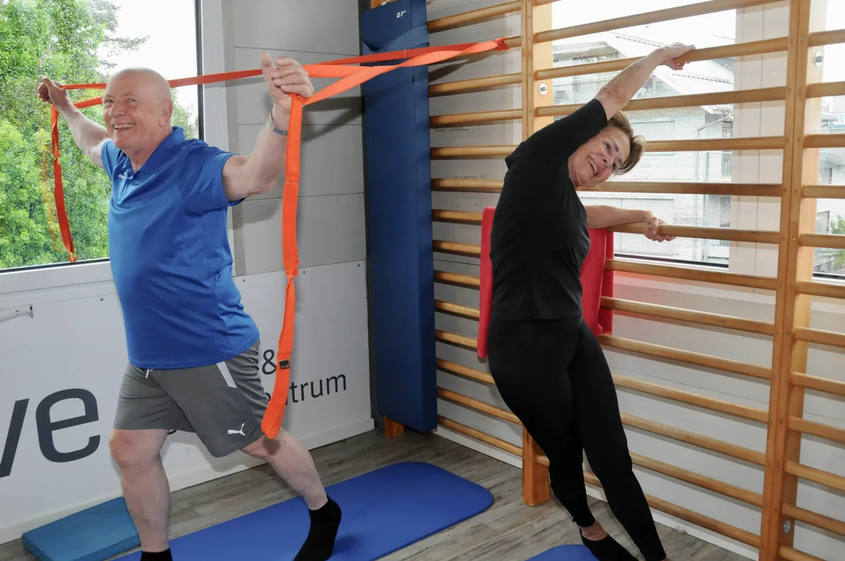 Man sieht ein Ehepaar beim Stretchtraining.
